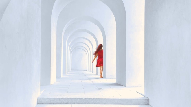 woman in red dress standing in white arch building